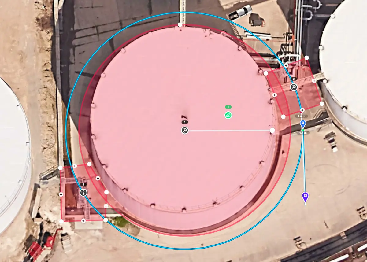 Misión de inspección vertical planificada alrededor de un tanque de almacenamiento, con zonas de restricción en rojo sobre el tanque y dos plataformas en su borde