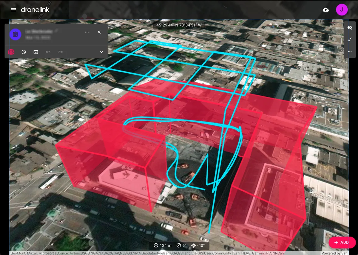 Vista previa 3D de una misión de construcción en un centro urbano, con zonas de restricción en rojo que impiden el vuelo alrededor de los edificios vecinos